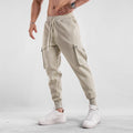 Men's loose-fit cotton sports trousers in apricot colour with ankle ties and multiple pockets, laid flat.