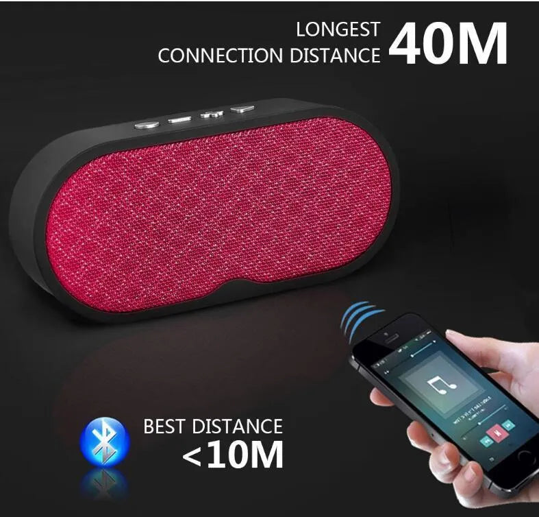 Portable grey Bluetooth wireless speaker with subwoofer and HD microphone on a table.