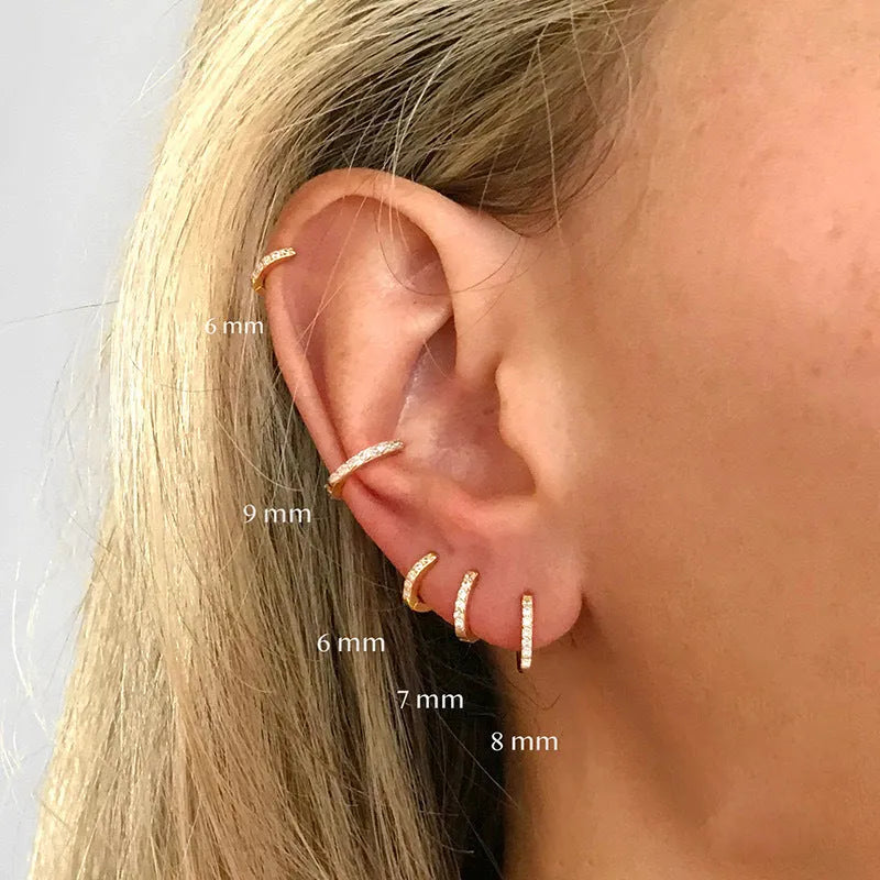 Gold, rose gold, and silver circle-shaped perforated stud earrings on a plain background.