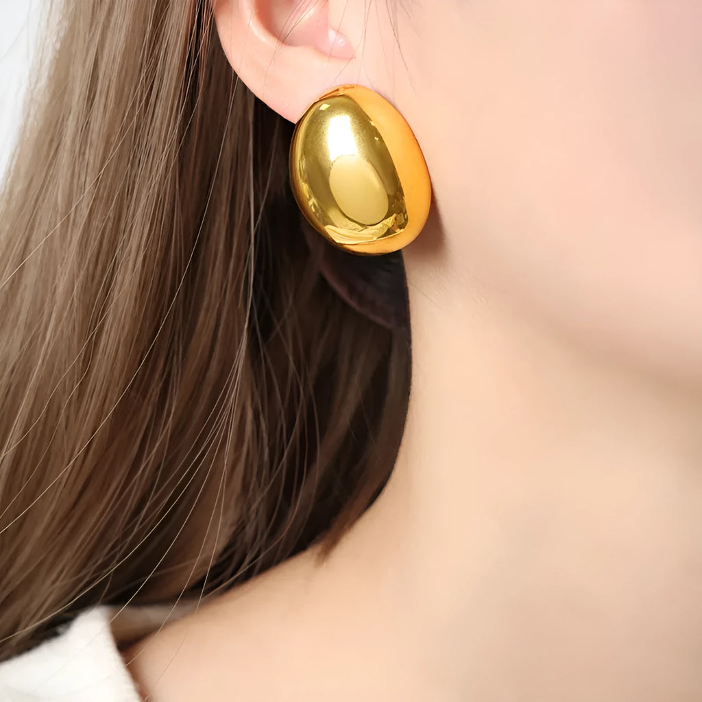 Geometric gold-coloured ear studs with glazed surface and line design details