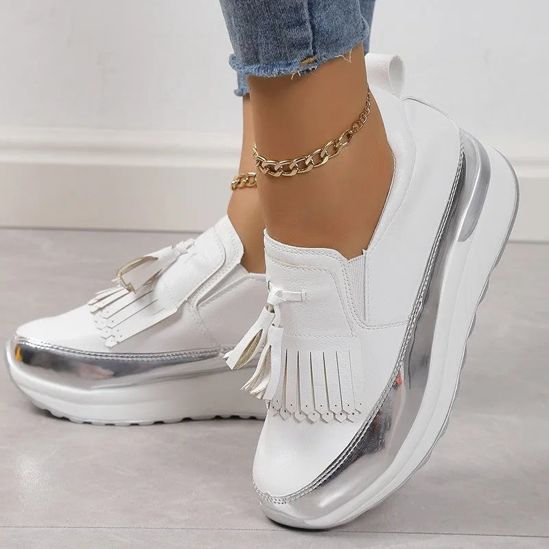 Women's black platform loafers with a tassel detail and a low wedge heel on a white background.