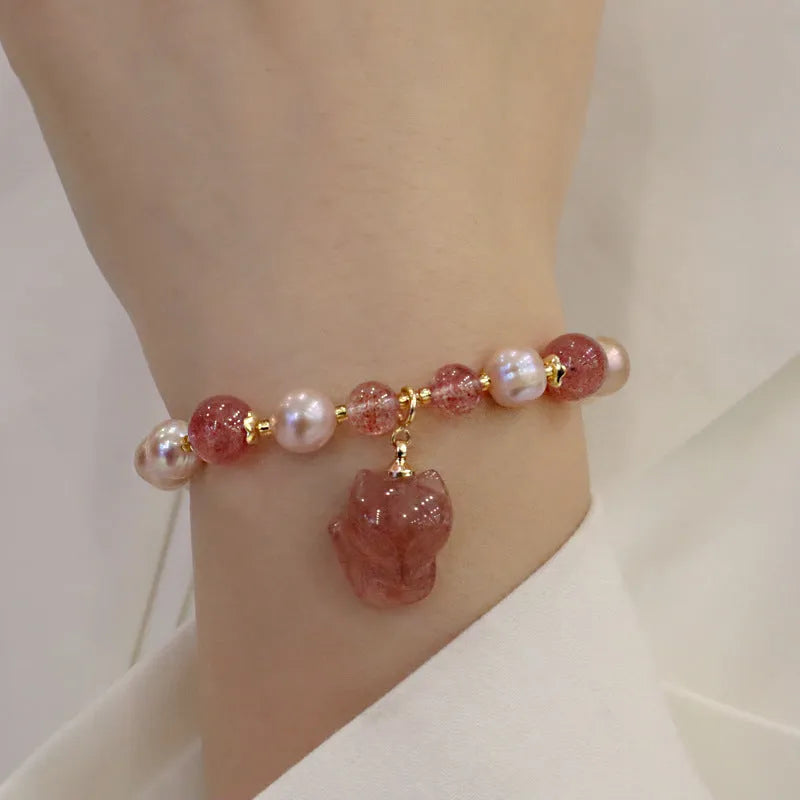 Women's light pink freshwater pearl bracelet with strawberry quartz and fox charm on wrist