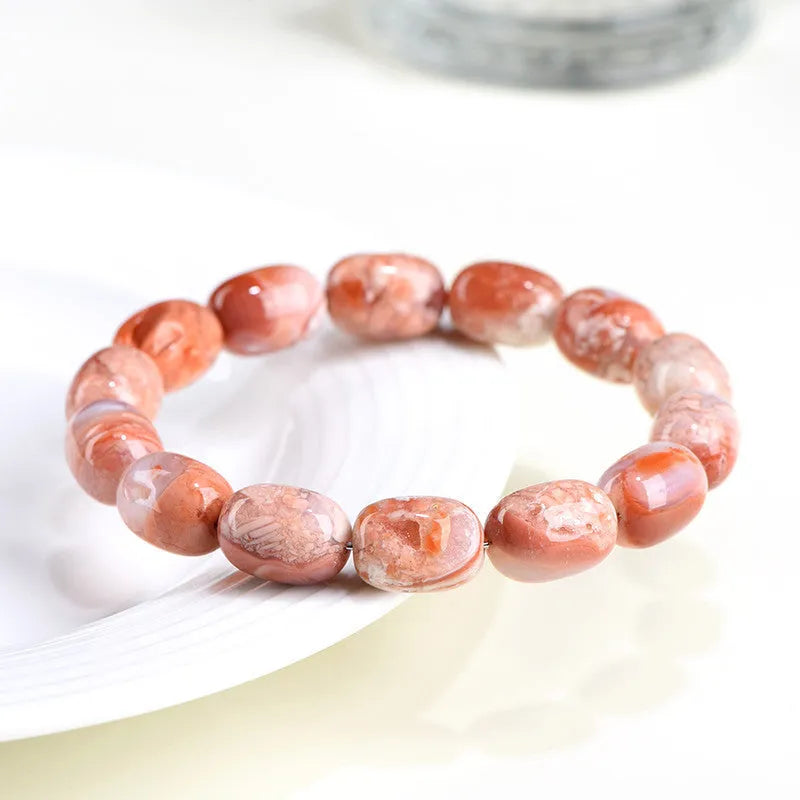 Natural cherry agate barrel bead bracelet with Ruyi symbols on a white background.