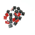 Black and white plastic self-adhesive wire clamps for organising flat cables on a surface.