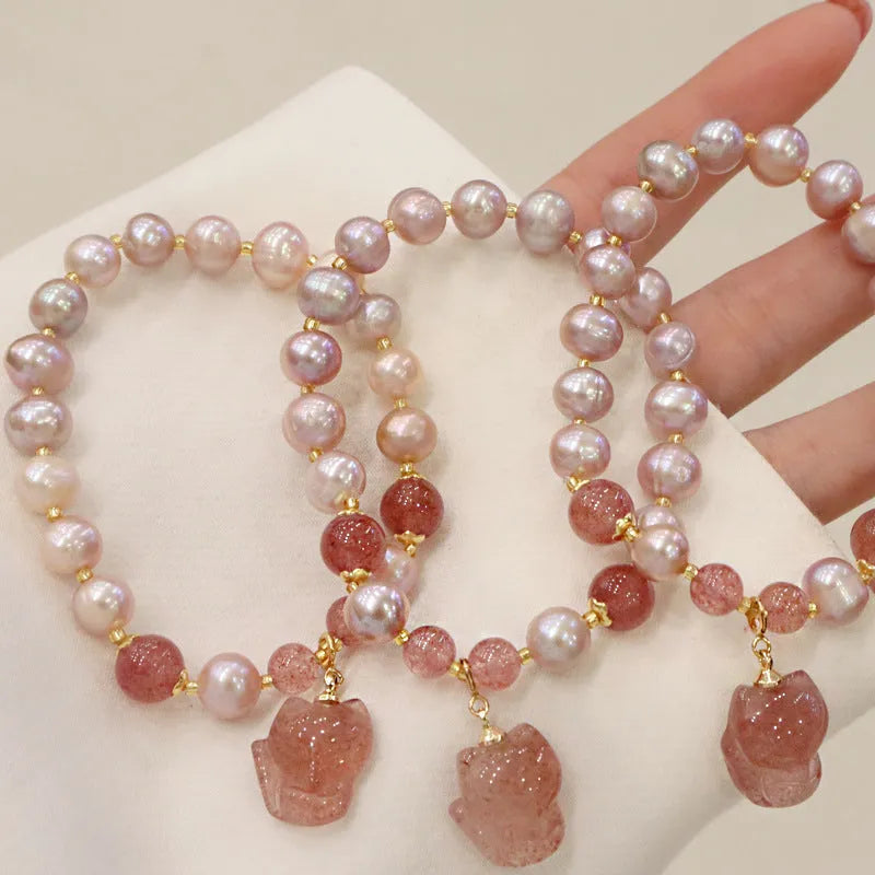 Women's light pink freshwater pearl bracelet with strawberry quartz and fox charm on wrist