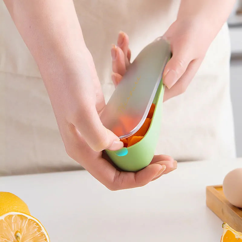 Dark green kitchen peeler with storage tube, non-slip handle, and stainless steel blade on a kitchen counter.