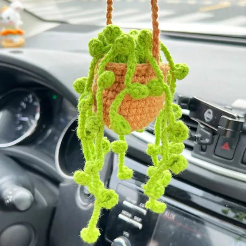 Green and white knitted wool car plant ornament hanging from a rope