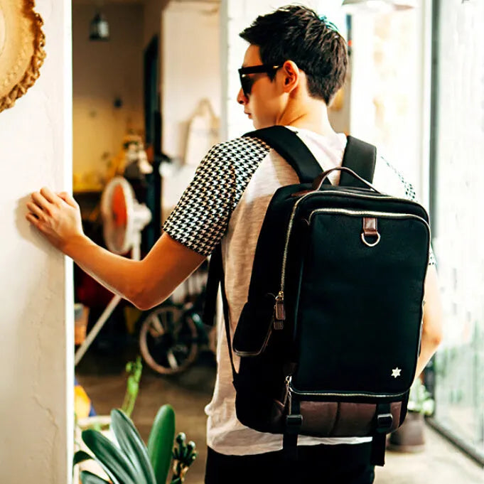 Men's modern Oxford fabric backpack in army green, showing front pockets and padded straps.
