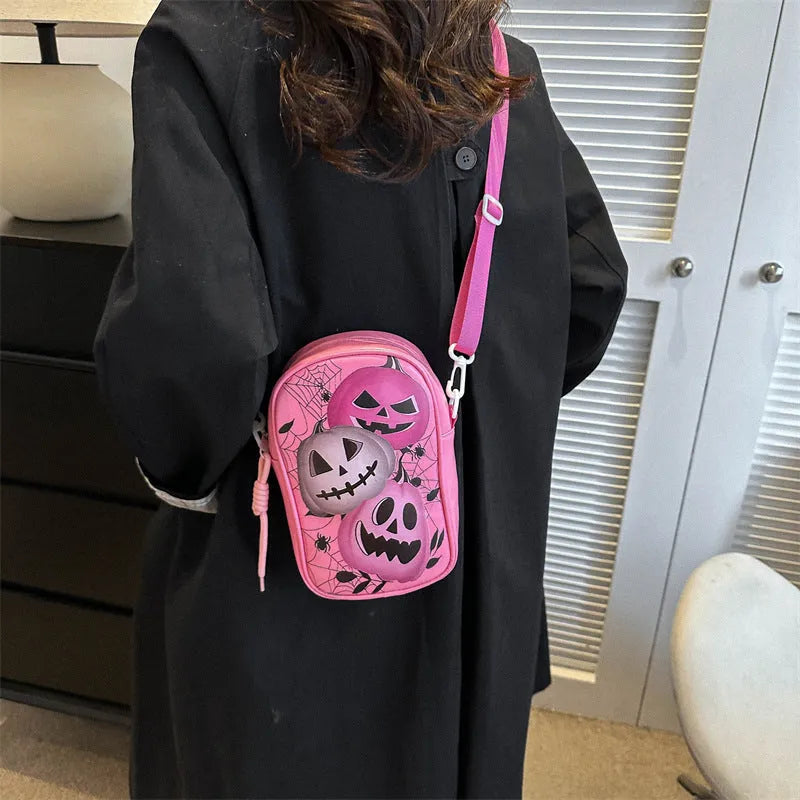 Black Halloween crossbody bag with orange pumpkin, white ghost, and bat graffiti print, shown worn across the body.