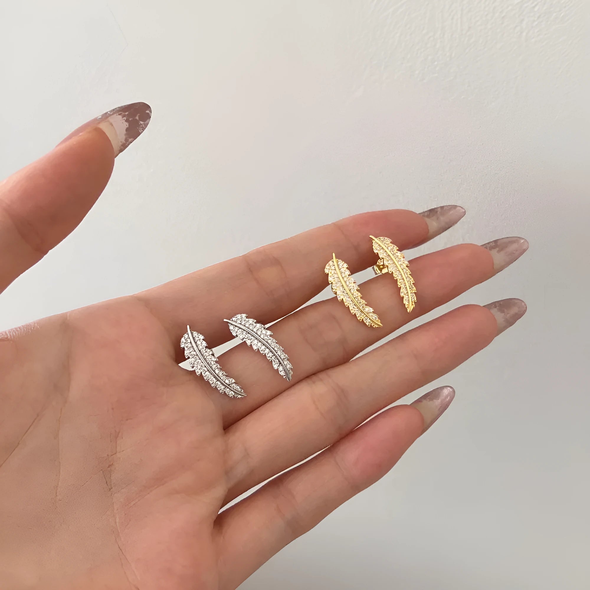 Leaf-shaped zircon inlaid S925 sterling silver stud earrings in gold colour on white background