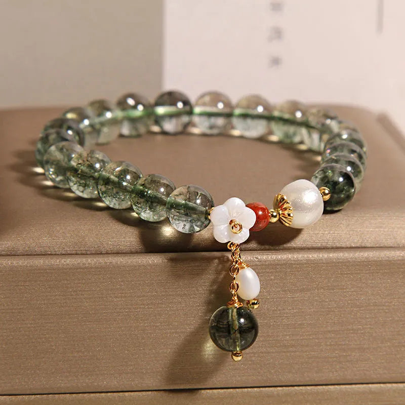 Green phantom quartz crystal bracelet for women with small shell flower and Bells of Ireland design details.