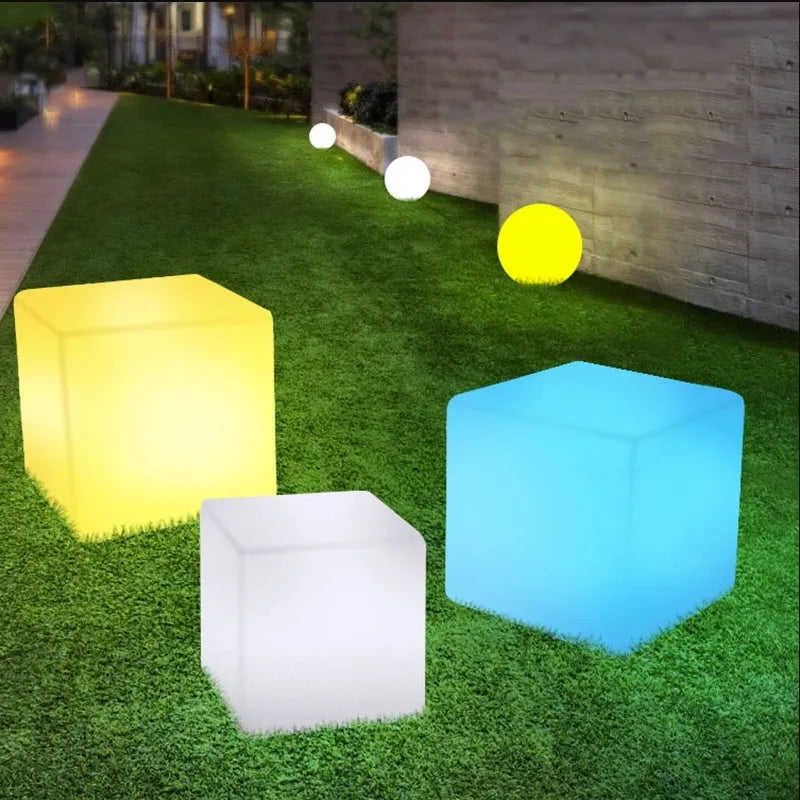 A white square cube LED stool light sitting on a patio, illustrating its modern design and outdoor use.
