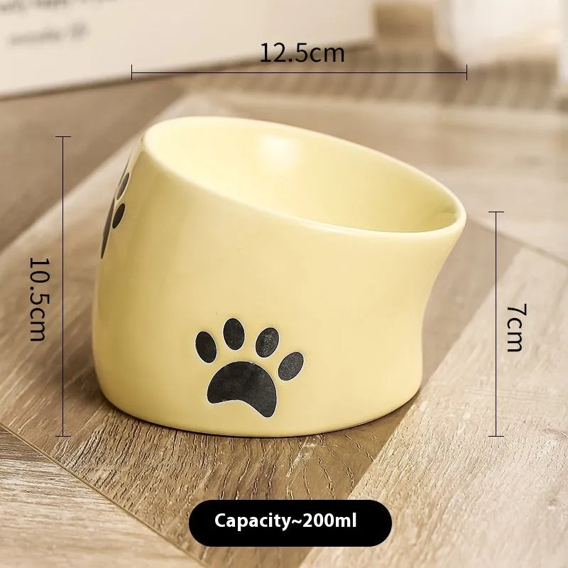Ceramic cat food bowl with high foot base in a cat's paw print design