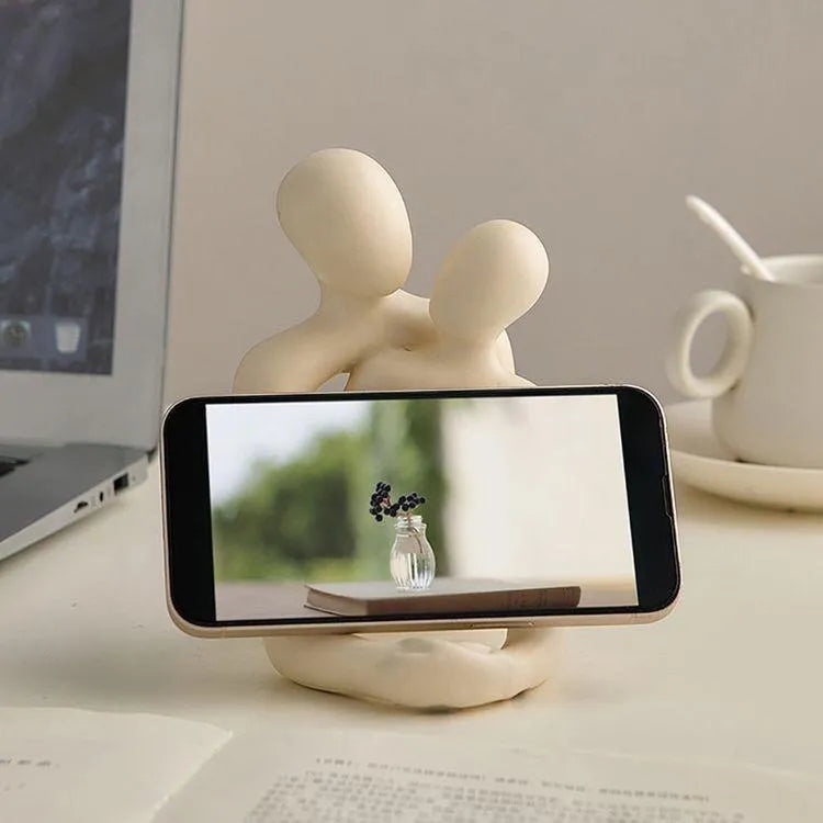 Modern minimalist resin statue of a couple in milky white or gold finish on a wooden surface.