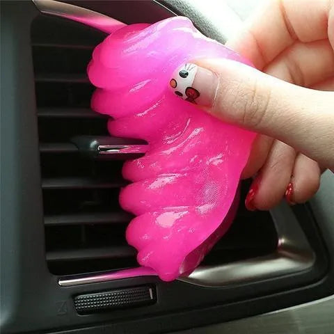Blue and yellow lumps of Magic Cleaning Gel adhesive putty for dust removal, shown with a car vent and keyboard.