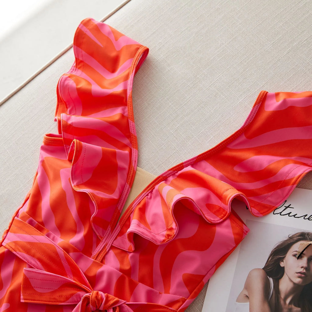 Women's deep V-neck one-piece swimsuit with ruffled shoulders and mesh stitching detail in a printing pattern.