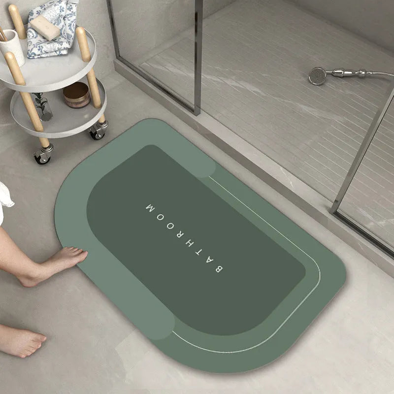 Machine woven bathroom floor mat in blue colour, shown in an oval shape on a tiled floor.