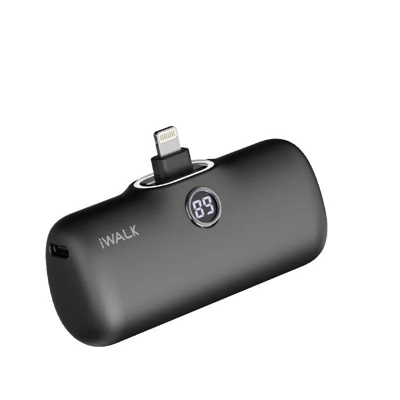 Small white cylindrical lipstick-style power bank showing digital battery percentage screen on a wooden table.