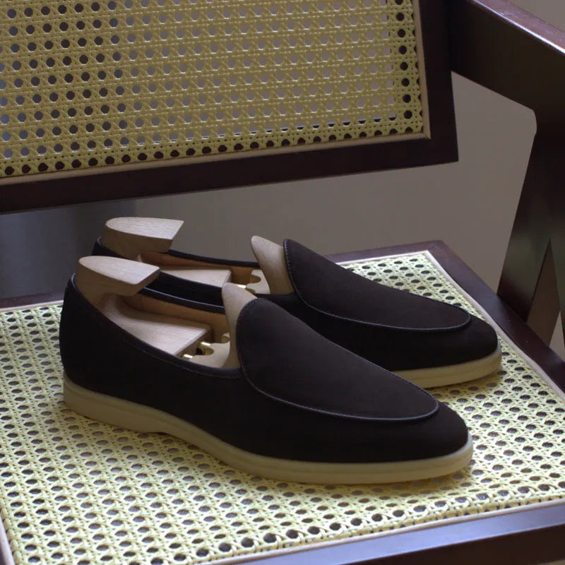 British handmade brown leather men's loafers with a flat TPR sole on a wooden surface.