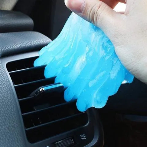 Blue and yellow lumps of Magic Cleaning Gel adhesive putty for dust removal, shown with a car vent and keyboard.