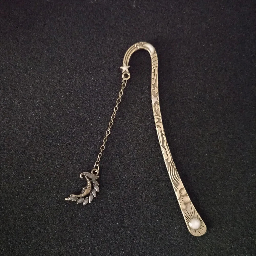 Metal bookmark with glowing five-pointed star and celestial sun moon stars design