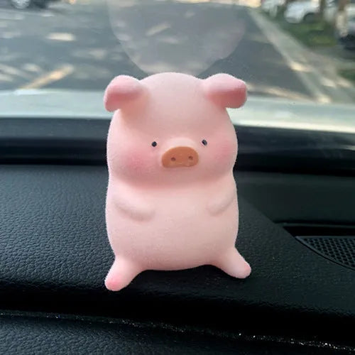 A cute cartoon pig resin figurine car decoration accessory on a dashboard.