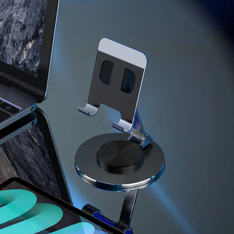 Aluminium alloy rotating mobile phone bracket in silver on a desk, showing three-axis joint and metal texture finish
