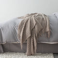 Small dark grey polyester nap blanket folded on a sofa, showing its 127x170cm size.