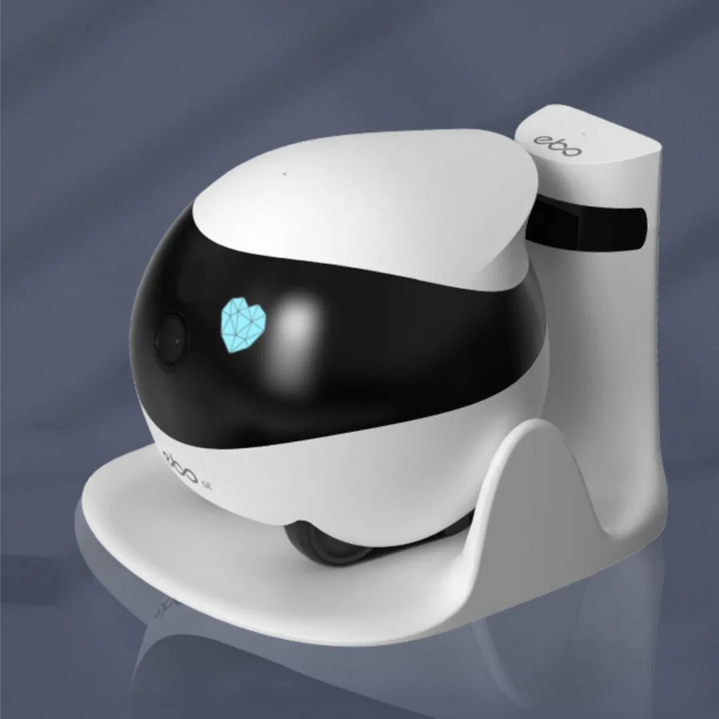 White smart home mobile robot camera with a lens and sensors on a charging dock.