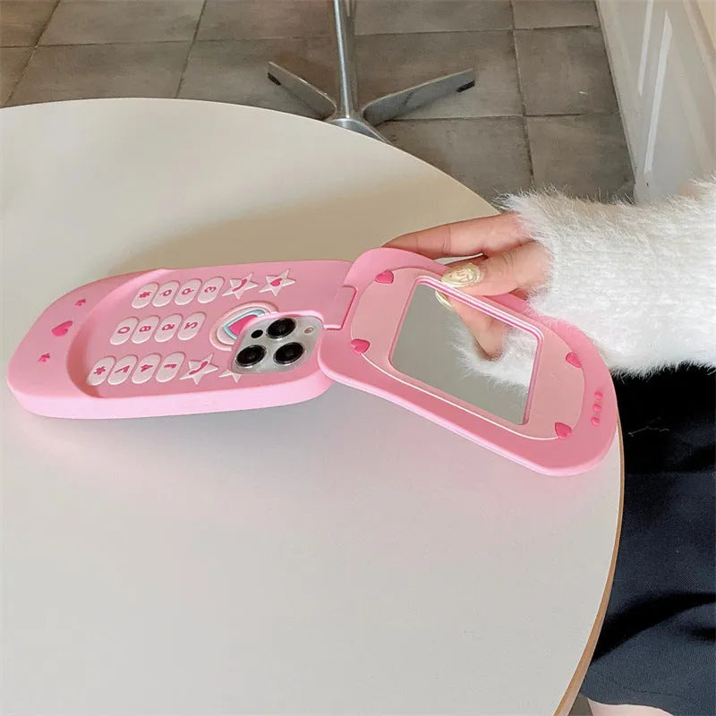 Light pink silicone flip phone case with built-in mirror for iPhone on a table