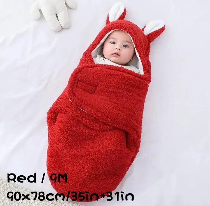 Baby wearing a grey adjustable fleece swaddle sleep sack with velcro wings