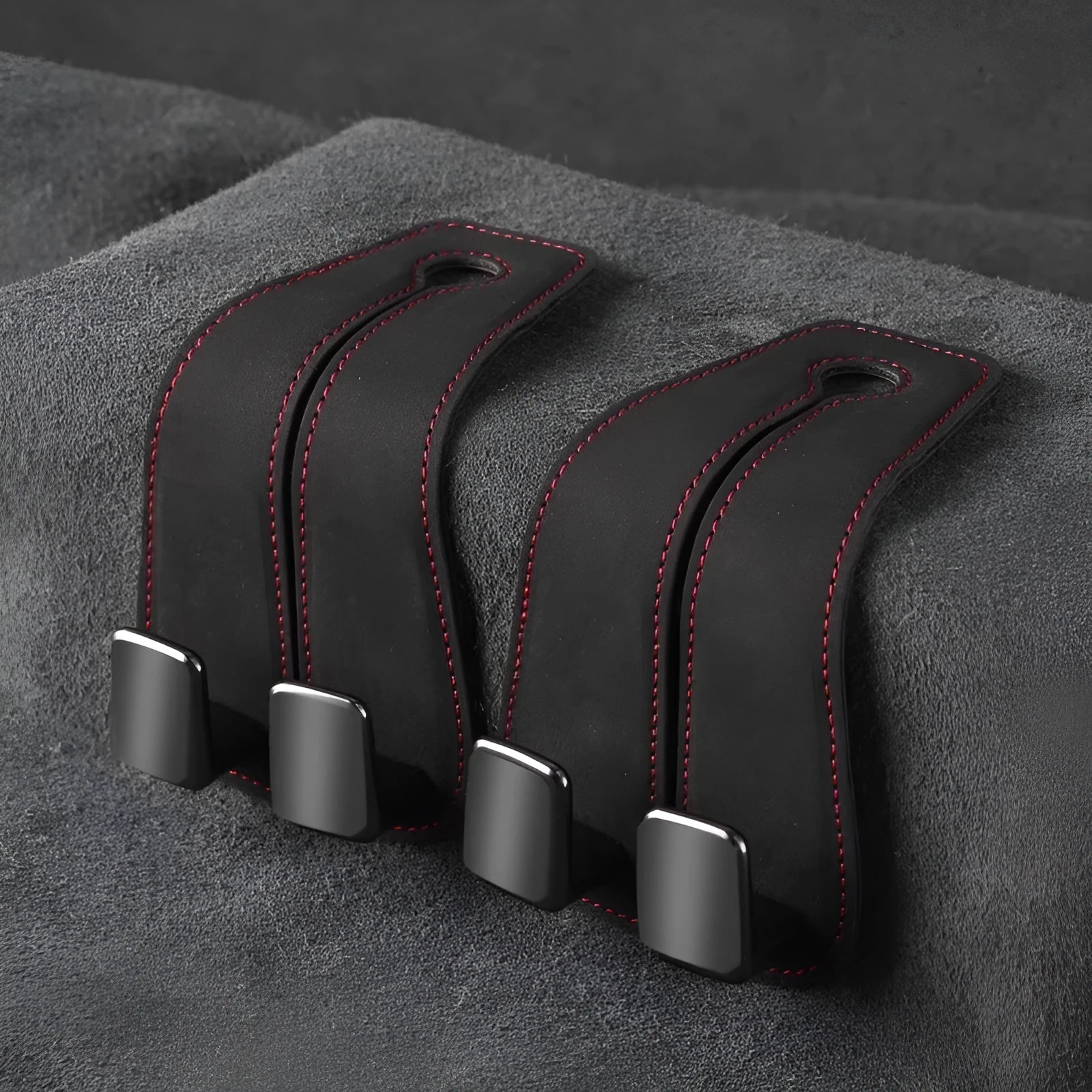 Black alloy car seat hook with suede covering attached to a grey car seatback.