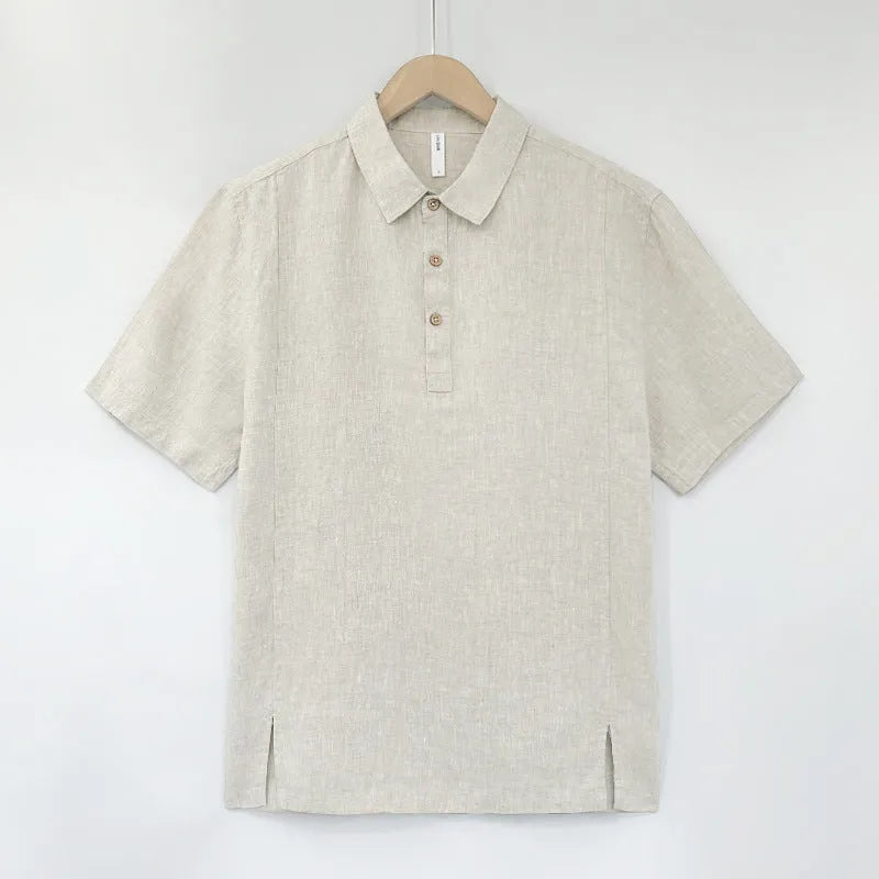 Man wearing a light grey green loose-fit linen top with thin lapels and short sleeves.