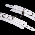 White PU sponge bondage set showing handcuffs, foot cuffs, and a neck scarf for adult play.