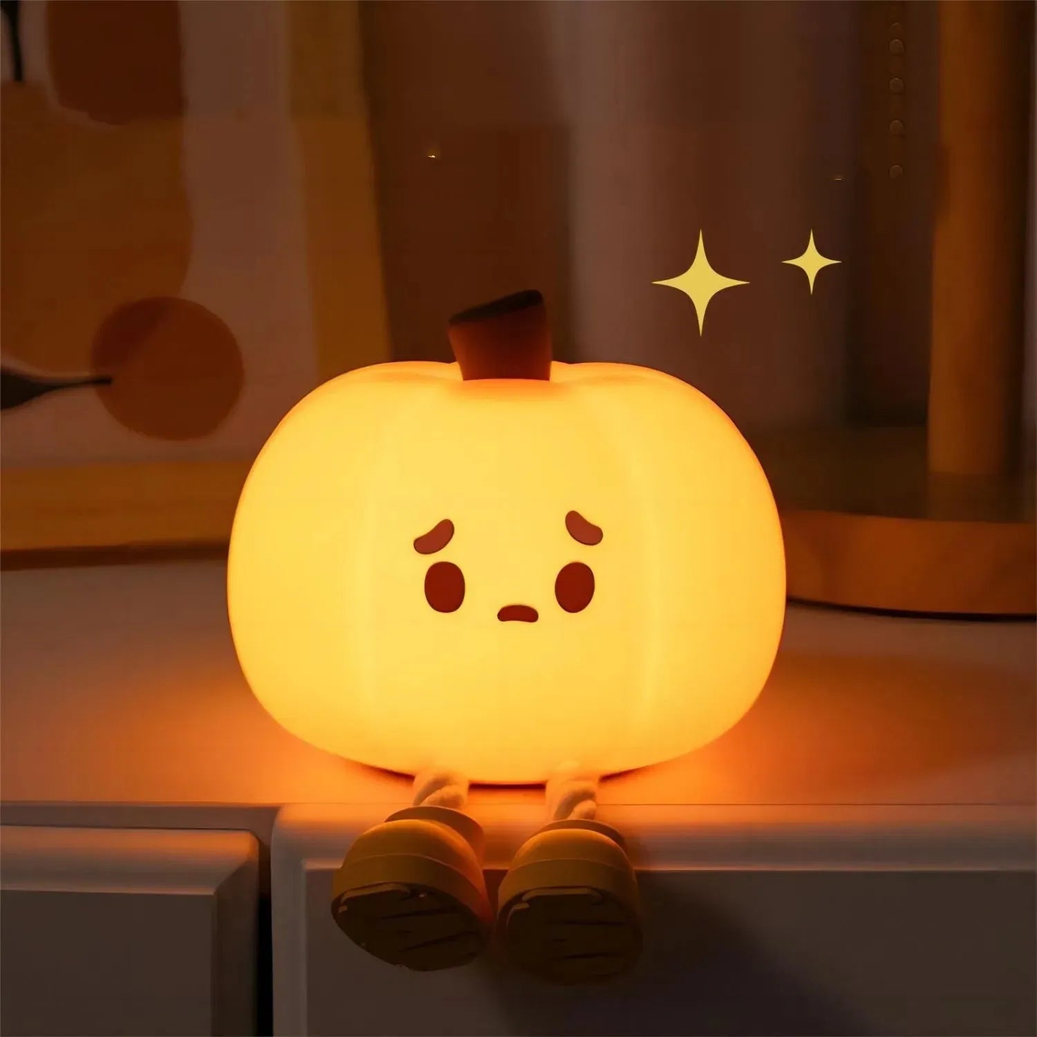 Soft orange silicone pumpkin-shaped night light with a gentle glow, sitting on a surface.