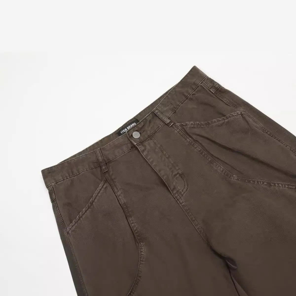 Men's brown loose-fit straight leg trousers with a high waist and wide-leg style on a hanger.