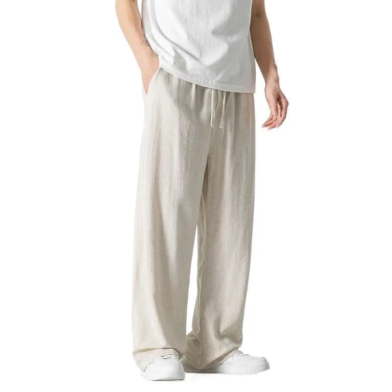 Man wearing beige bamboo fibre drawstring waist trousers with a cropped, straight leg.