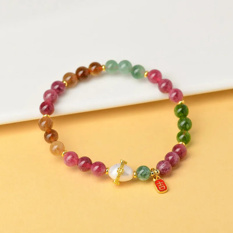Geometric chalcedony stone bracelet with tourmaline colour beads on a wrist.