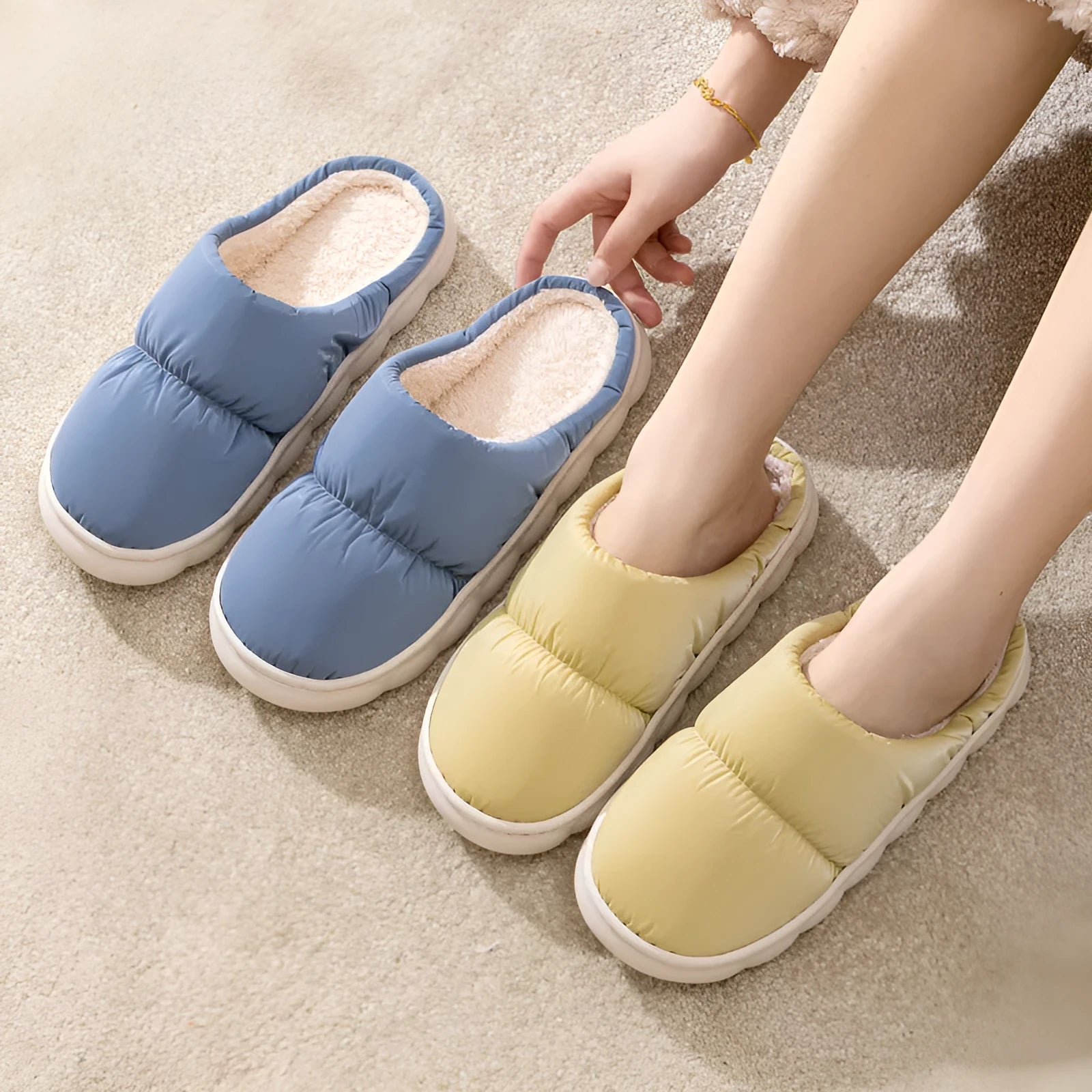 A pair of blue down cotton winter slippers with a thick rubber sole and plush lining on a wooden floor.