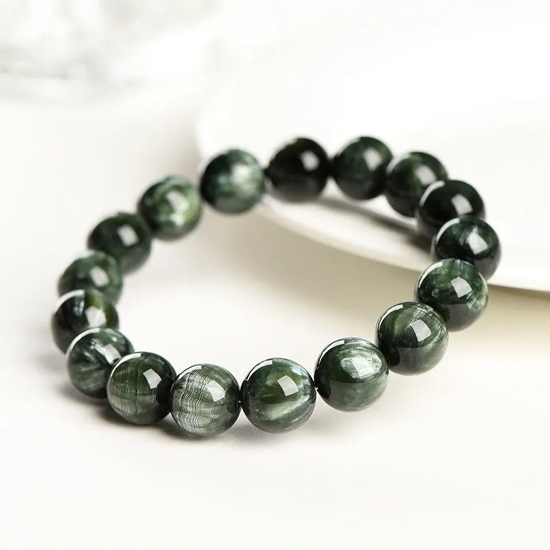 A bracelet made of polished green dragon crystal round beads with a geometric Ruyi design element.