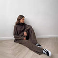 Women's dark grey acrylic knit suit with side-slit hem sweater and matching trousers laid flat.