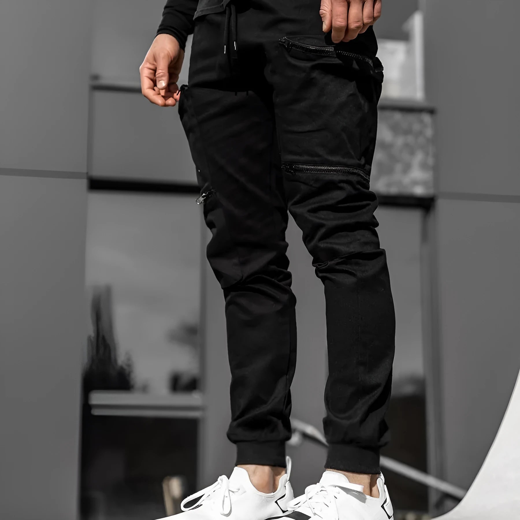 Men's tight fit multi-pocket cotton trousers in black, shown with multiple front pockets and tethered details on waistband.