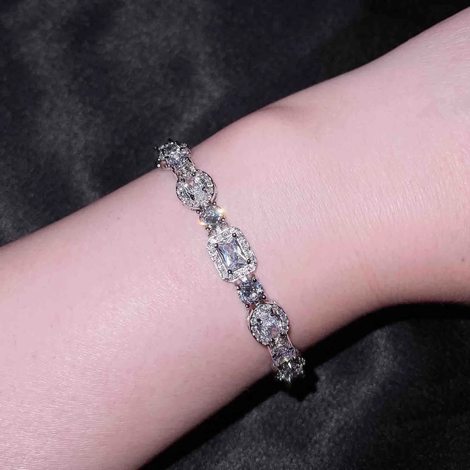 Close-up of a women's geometric silver bracelet with sparkling inlaid zircon stones and a lobster clasp.