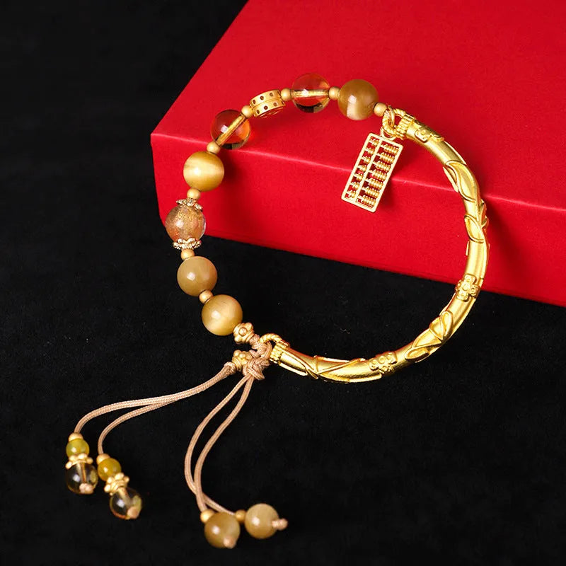 Close-up of a women's beaded bracelet with diamond-shaped tigereye and citrine stones and copper details.