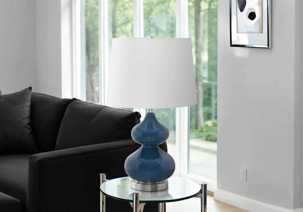 Tall crystal glass desk lamp with a blue cloth shade on a wooden desk.