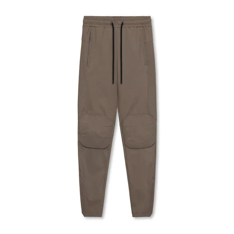 Man wearing dark grey tapered fitness trousers with adjustable ankle ties during a workout.