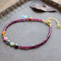Close-up of a purple garnet anklet with a geometric design on a female ankle.
