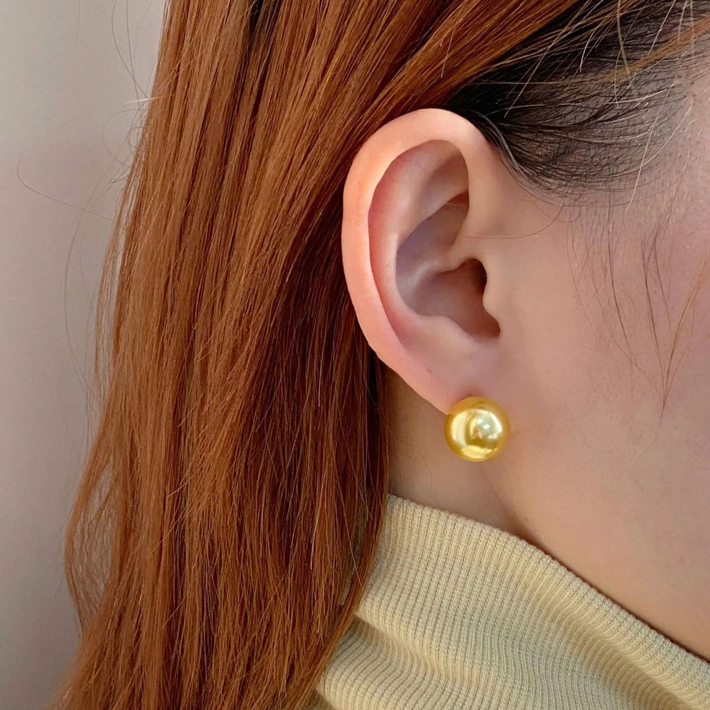 Close-up of a women's large pearl stud earring with an eight-point geometric silver star setting.