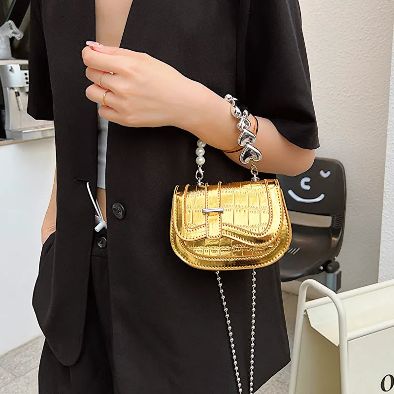 Silver women's PU leather mini tote saddle crossbody bag on a table.