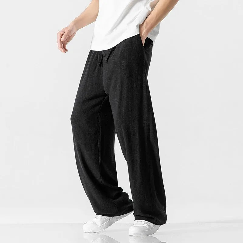 Man wearing beige bamboo fibre drawstring waist trousers with a cropped, straight leg.